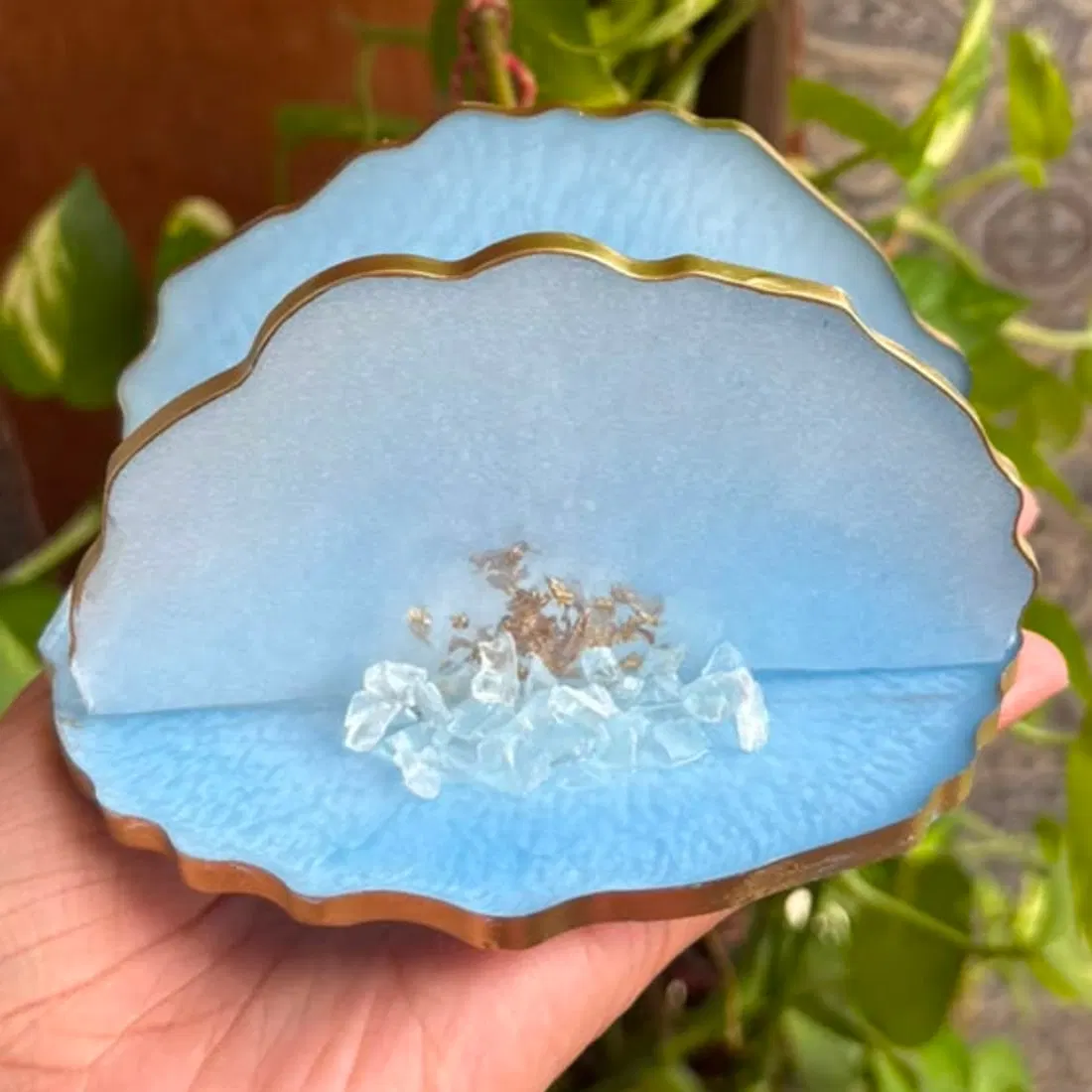The blue resin tissue holder seen from the front: the scalloped base and one upright wall, the gilded edge catching the light, with crushed glass and a scatter of gold flake set into the pour