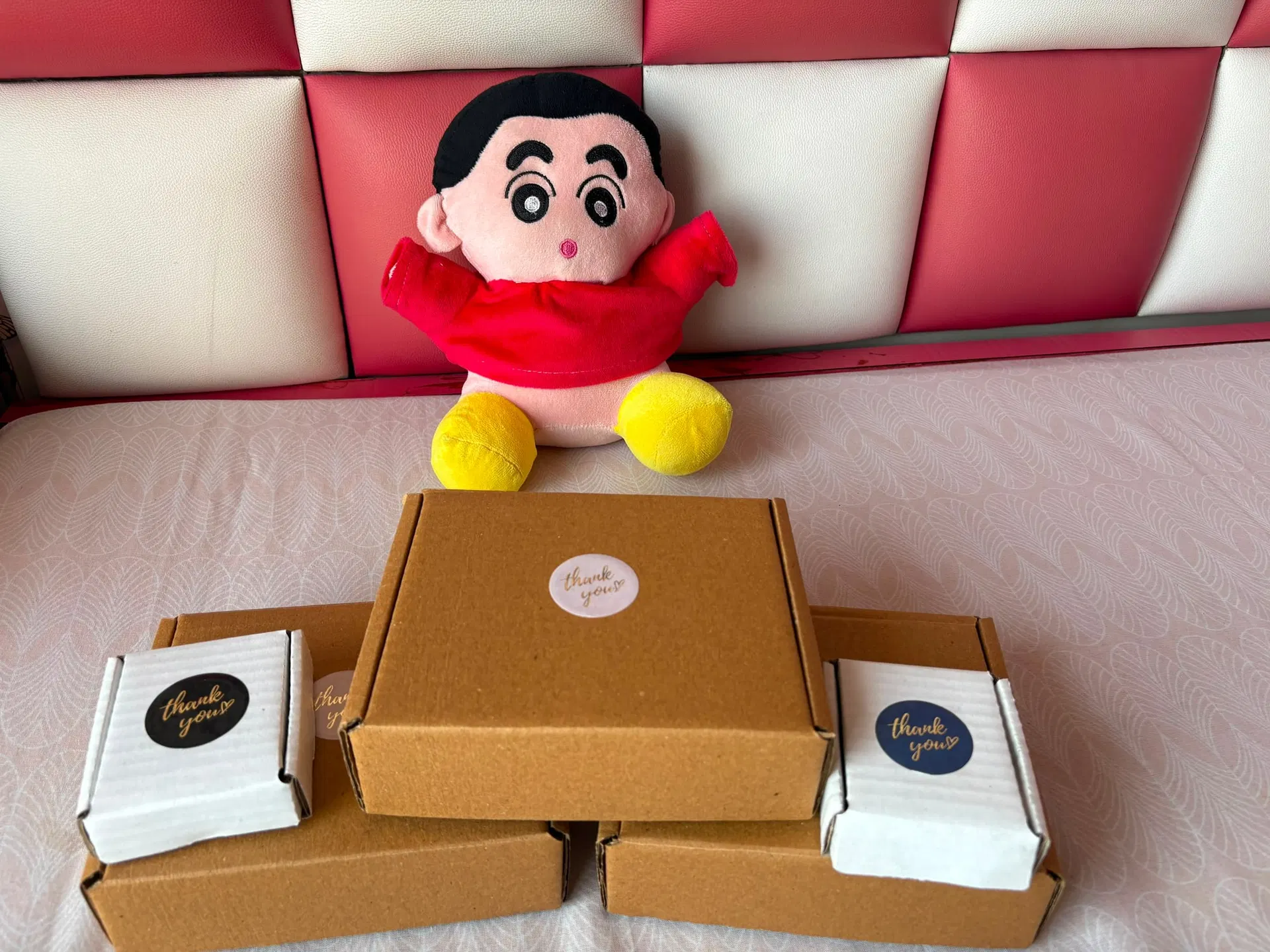 A stack of kraft and white shipping boxes with thank-you stickers, ready to go out